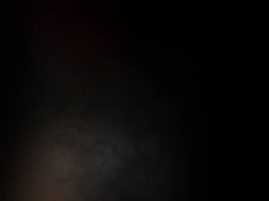 Siyah bir arka planın önünde duran takım elbiseli ve kravatlı bir adam.