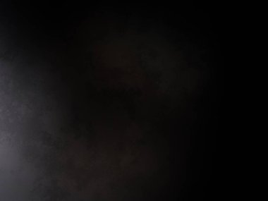 Siyah bir arka planın önünde duran takım elbiseli ve kravatlı bir adam.