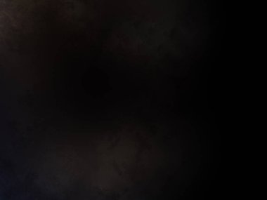 Takım elbiseli ve kravatlı bir adam karanlık bir arka planın önünde duruyor.