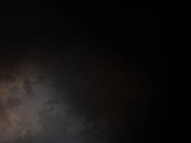 Siyah gömlekli ve kravatlı bir adam siyah bir duvarın önünde duruyor.