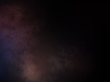 Takım elbiseli ve kravatlı bir adam karanlık bir arka planın önünde duruyor.