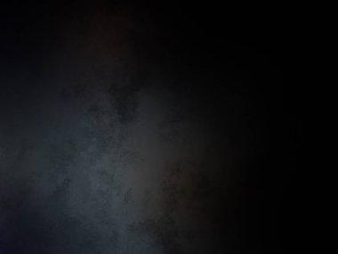 Siyah bir arka planın önünde duran takım elbiseli ve kravatlı bir adam.