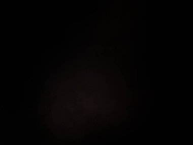 Siyah bir arka planın önünde duran takım elbiseli ve kravatlı bir adam.