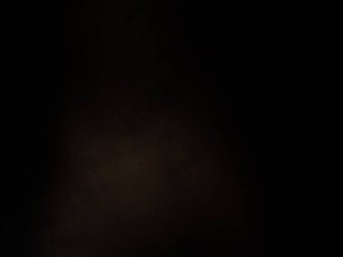 Siyah bir arka planın önünde duran takım elbiseli ve kravatlı bir adam.