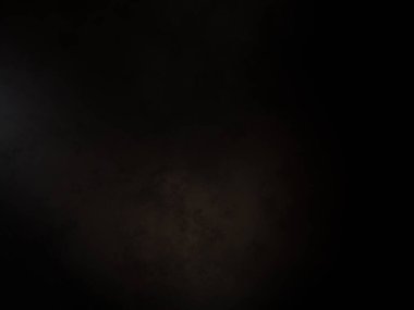 Siyah bir arka planın önünde duran takım elbiseli ve kravatlı bir adam.