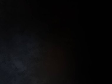 Siyah bir arka planın önünde duran takım elbiseli ve kravatlı bir adam.