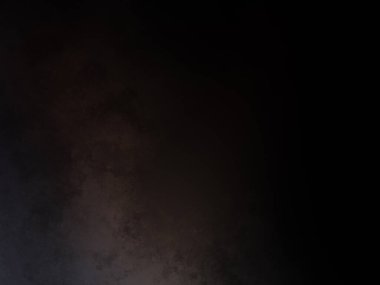 Takım elbiseli ve kravatlı bir adam karanlık bir arka planın önünde duruyor.