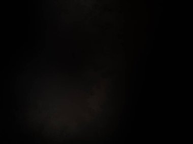 Siyah bir arka planın önünde duran takım elbiseli ve kravatlı bir adam.