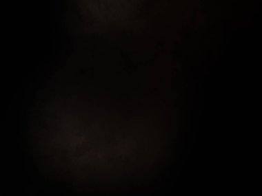 Siyah bir arka planın önünde duran takım elbiseli ve kravatlı bir adam.