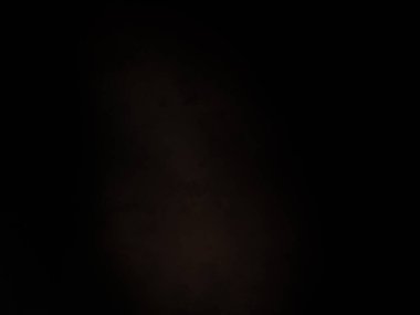 Karanlıkta duran takım elbiseli ve kravatlı bir adam.