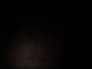 Siyah bir arka planın önünde duran takım elbiseli ve kravatlı bir adam.