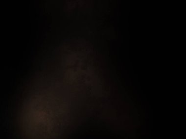 Siyah bir arka planın önünde duran takım elbiseli ve kravatlı bir adam.