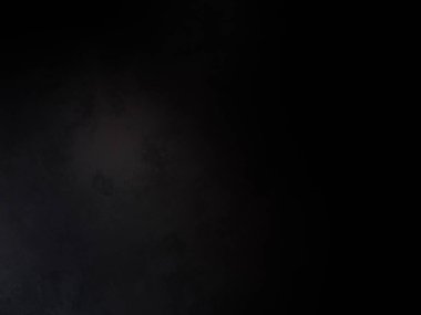 Siyah bir arka planın önünde duran takım elbiseli ve kravatlı bir adam.