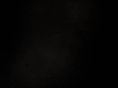 Siyah bir arka planın önünde duran takım elbiseli ve kravatlı bir adam.