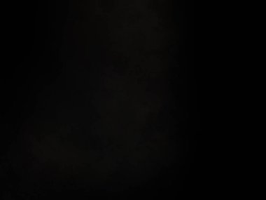 Siyah bir arka planın önünde duran takım elbiseli ve kravatlı bir adam.