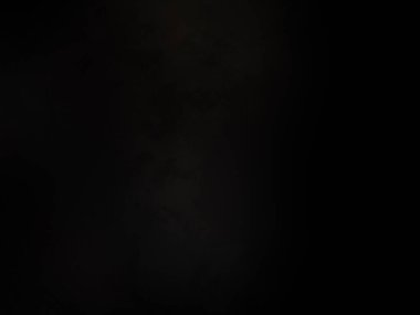 Siyah bir arka planın önünde duran takım elbiseli ve kravatlı bir adam.