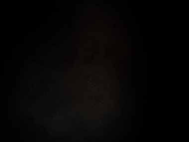 Siyah bir arka planın önünde duran takım elbiseli ve kravatlı bir adam.