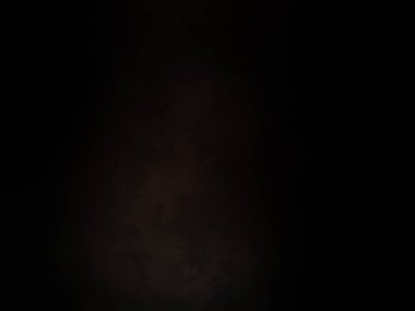 Siyah bir arka planın önünde duran takım elbiseli ve kravatlı bir adam.