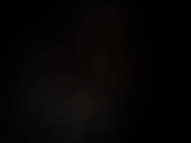 Siyah bir arka planın önünde duran takım elbiseli ve kravatlı bir adam.