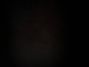 Siyah bir arka planın önünde duran takım elbiseli ve kravatlı bir adam.