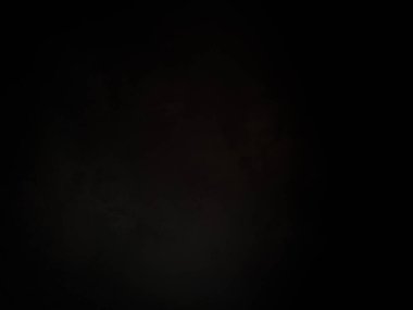 Siyah bir arka planın önünde duran takım elbiseli ve kravatlı bir adam.