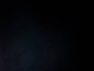 Siyah bir arka planın önünde duran takım elbiseli ve kravatlı bir adam.