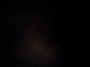 Siyah bir arka planın önünde duran takım elbiseli ve kravatlı bir adam.