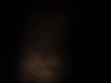 Takım elbiseli ve kravatlı bir adam karanlık bir arka planın önünde duruyor.