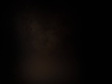 Siyah bir arka planın önünde duran takım elbiseli ve kravatlı bir adam.