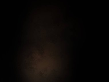 Siyah bir arka planın önünde duran takım elbiseli ve kravatlı bir adam.