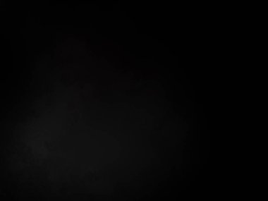 Siyah bir arka planın önünde duran takım elbiseli ve kravatlı bir adam.