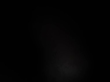 Siyah bir arka planın önünde duran takım elbiseli ve kravatlı bir adam.