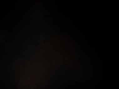 Siyah bir arka planın önünde duran takım elbiseli ve kravatlı bir adam.