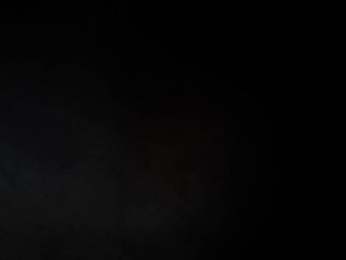 Siyah bir arka planın önünde duran takım elbiseli ve kravatlı bir adam.