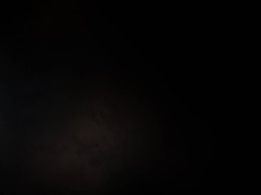 Siyah bir arka planın önünde duran takım elbiseli ve kravatlı bir adam.