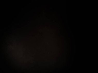 Siyah bir arka planın önünde duran takım elbiseli ve kravatlı bir adam.