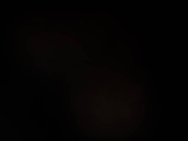 Siyah bir arka planın önünde duran takım elbiseli ve kravatlı bir adam.