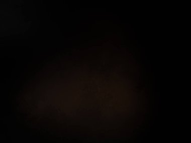 Siyah bir arka planın önünde duran takım elbiseli ve kravatlı bir adam.