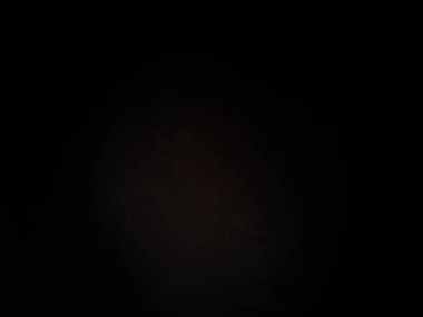 Siyah bir arka planın önünde duran takım elbiseli ve kravatlı bir adam.