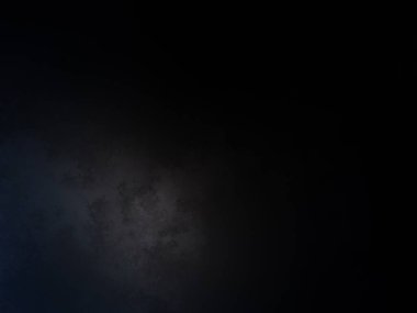 Takım elbiseli ve kravatlı bir adam karanlık bir arka planın önünde duruyor.