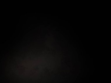 Siyah bir arka planın önünde duran takım elbiseli ve kravatlı bir adam.