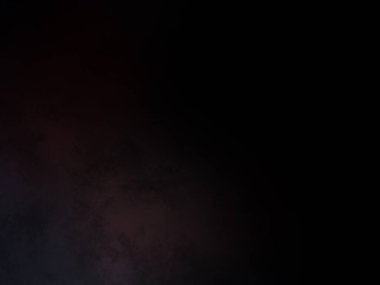 Siyah bir arka planın önünde duran takım elbiseli ve kravatlı bir adam.