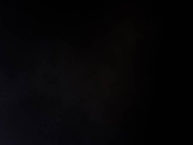 Siyah bir arka planın önünde duran takım elbiseli ve kravatlı bir adam.