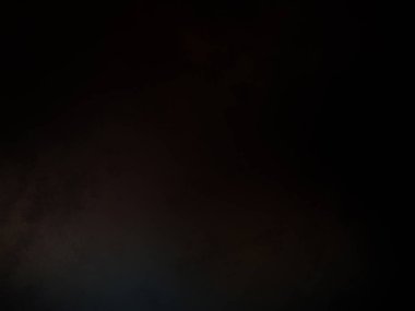 Siyah bir arka planın önünde duran takım elbiseli ve kravatlı bir adam.