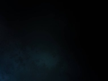 Takım elbiseli ve kravatlı bir adam karanlık bir arka planın önünde duruyor.