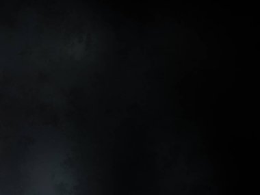 Siyah bir arka planın önünde duran takım elbiseli ve kravatlı bir adam.