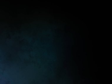 Takım elbiseli ve kravatlı bir adam karanlık bir arka planın önünde duruyor.