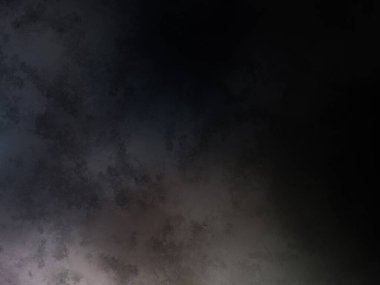 Takım elbiseli ve kravatlı bir adam karanlık bir arka planın önünde duruyor.