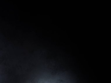 Siyah bir arka planın önünde duran takım elbiseli ve kravatlı bir adam.