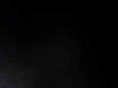 Siyah bir arka planın önünde duran takım elbiseli ve kravatlı bir adam.